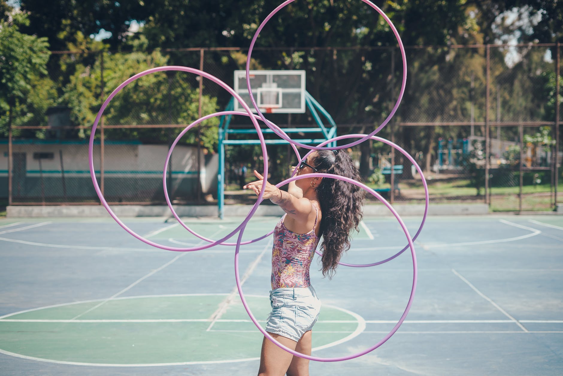 girl in printed top and denim shorts juggling hula hoops